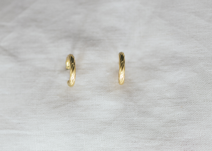 Gold hoop earrings on a light gray fabric background