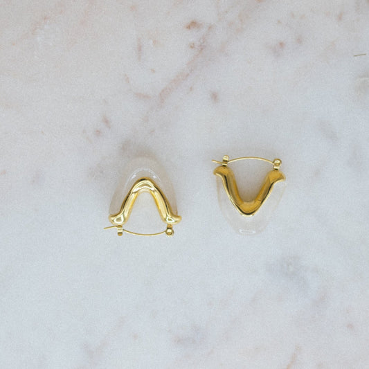 Gold U-shaped earrings on a marble surface
