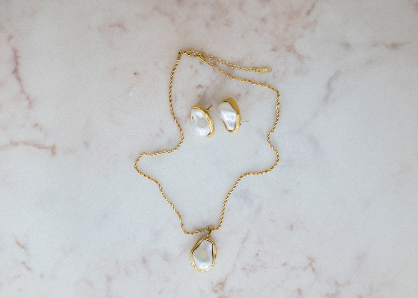 Gold necklace and earrings on a marble surface