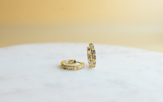 Gold hoop earrings with embedded stones on a white surface