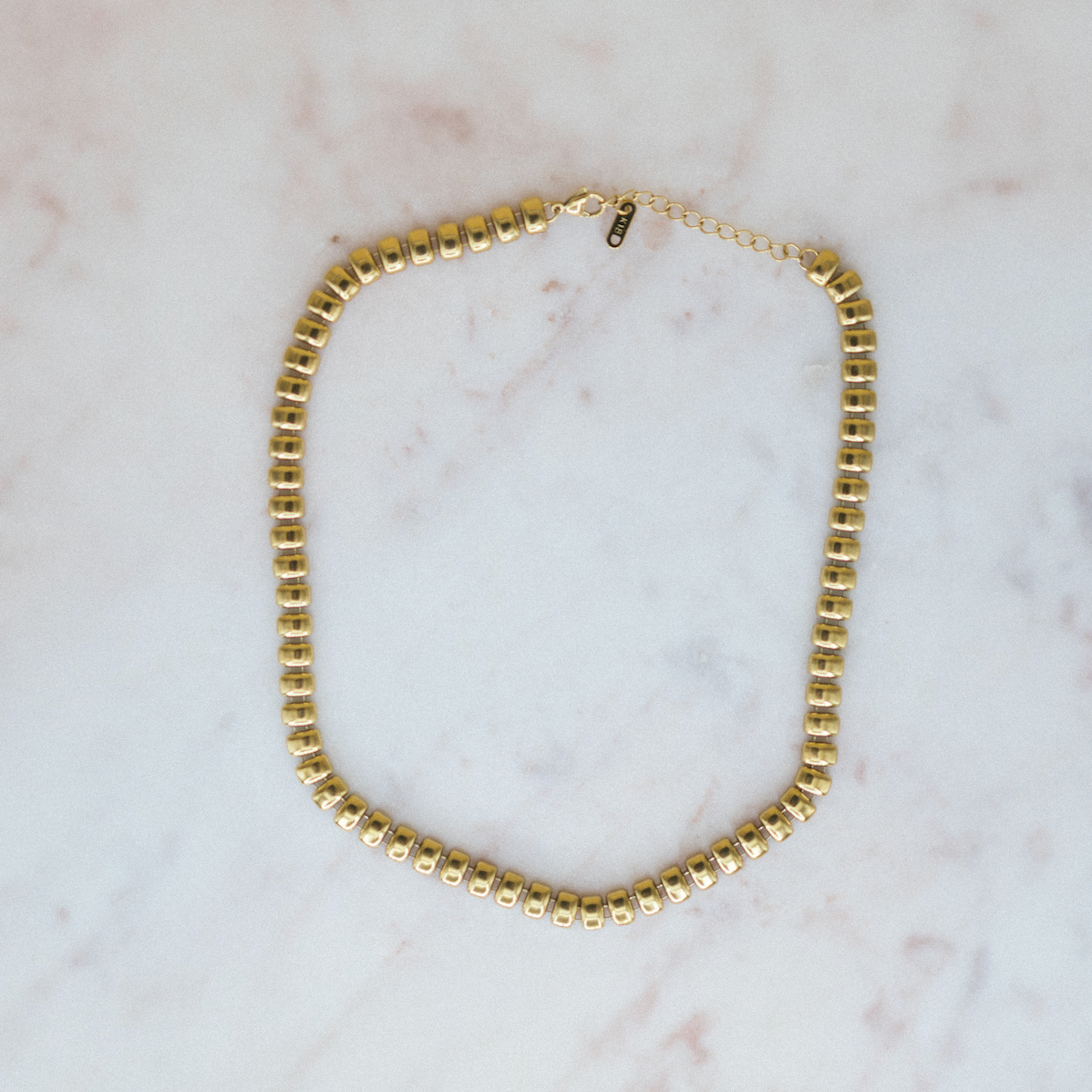 Gold beaded necklace on a marble surface