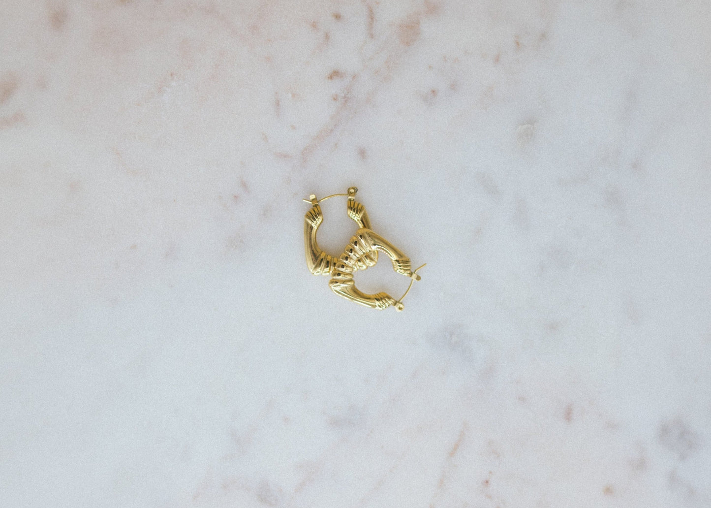 Gold hoop earring on a marble surface