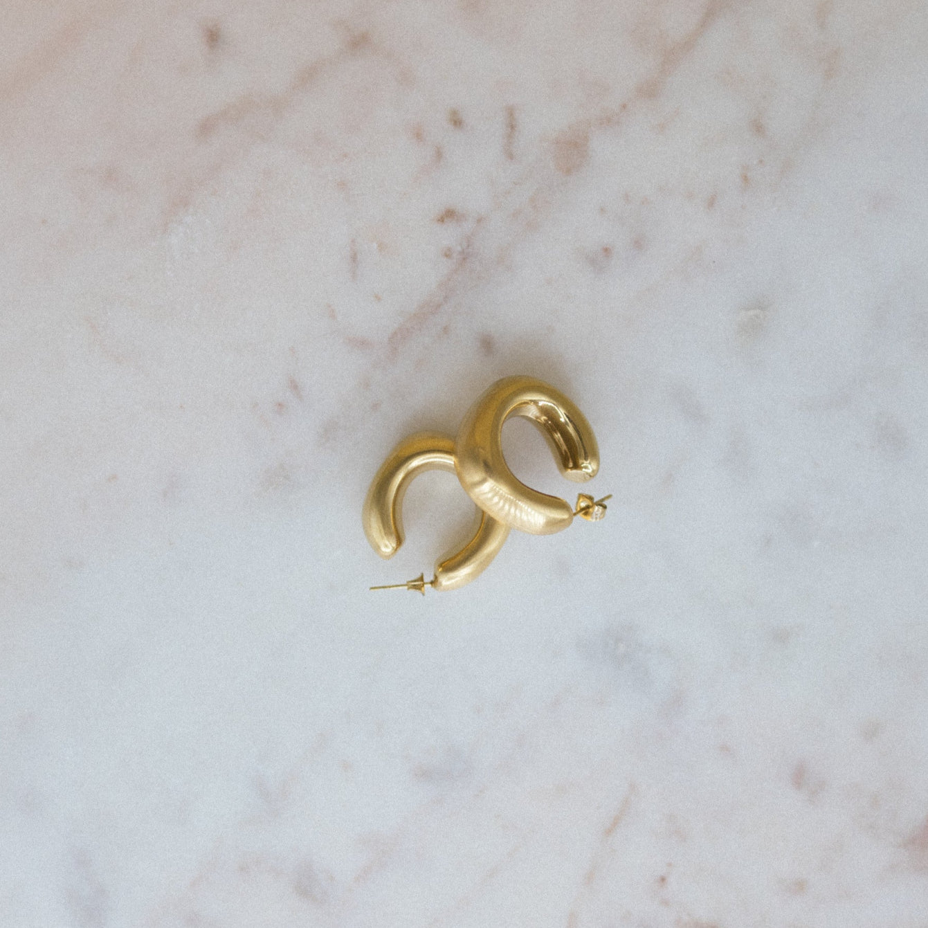 Gold hoop earrings on a marble surface
