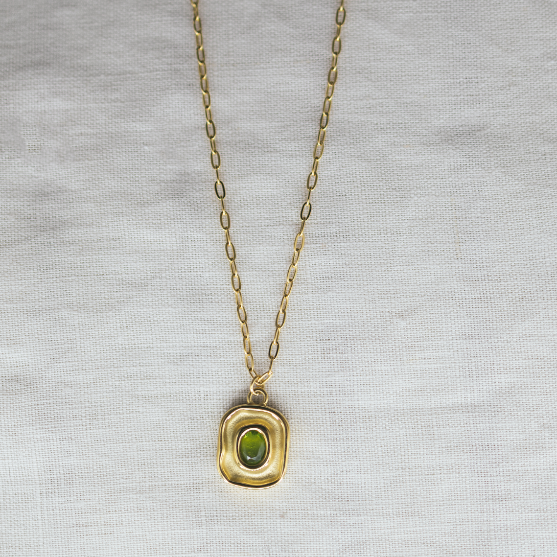 Luxe Leaf Pendant - green zircon pendant necklace. Gold necklace with a green pendant on a light gray background