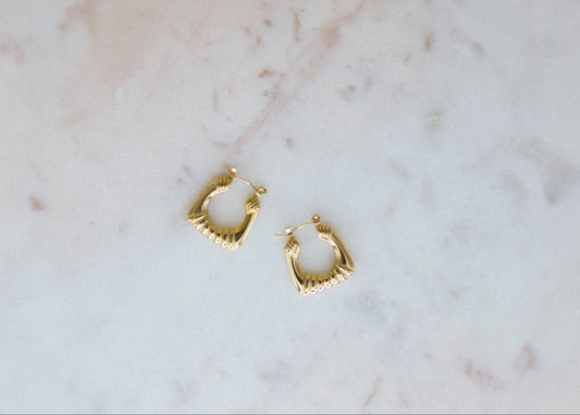 Bold Balance Hoops. Gold hoop earrings on a marble surface