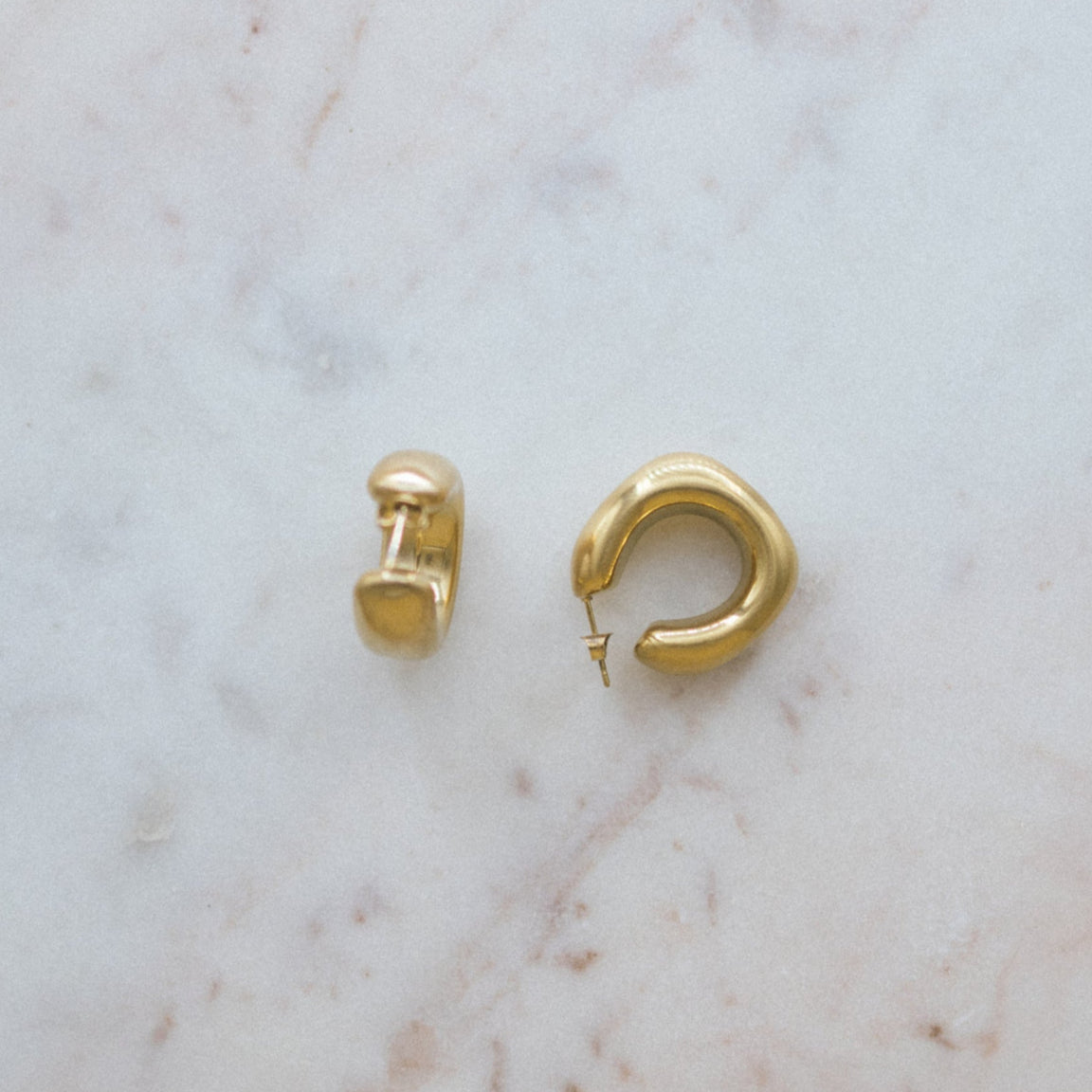 Gold hoop earrings on a marble surface