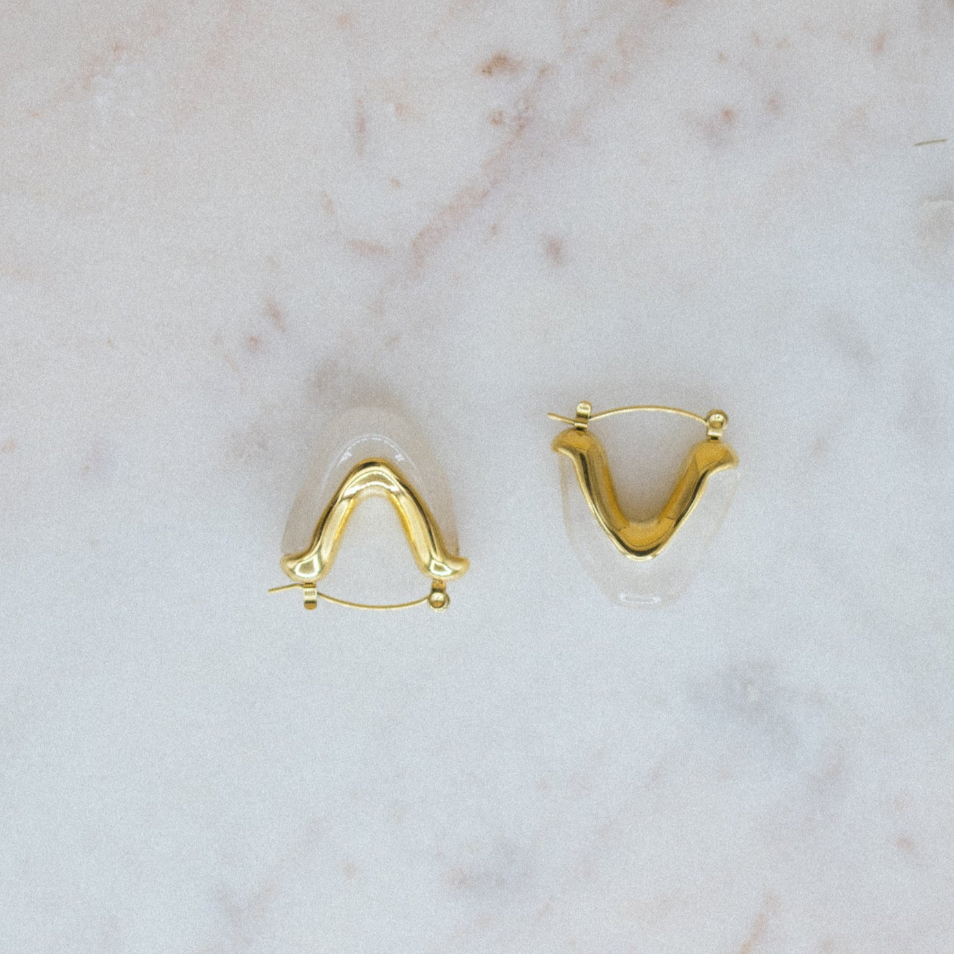 Gold U-shaped earrings on a marble surface