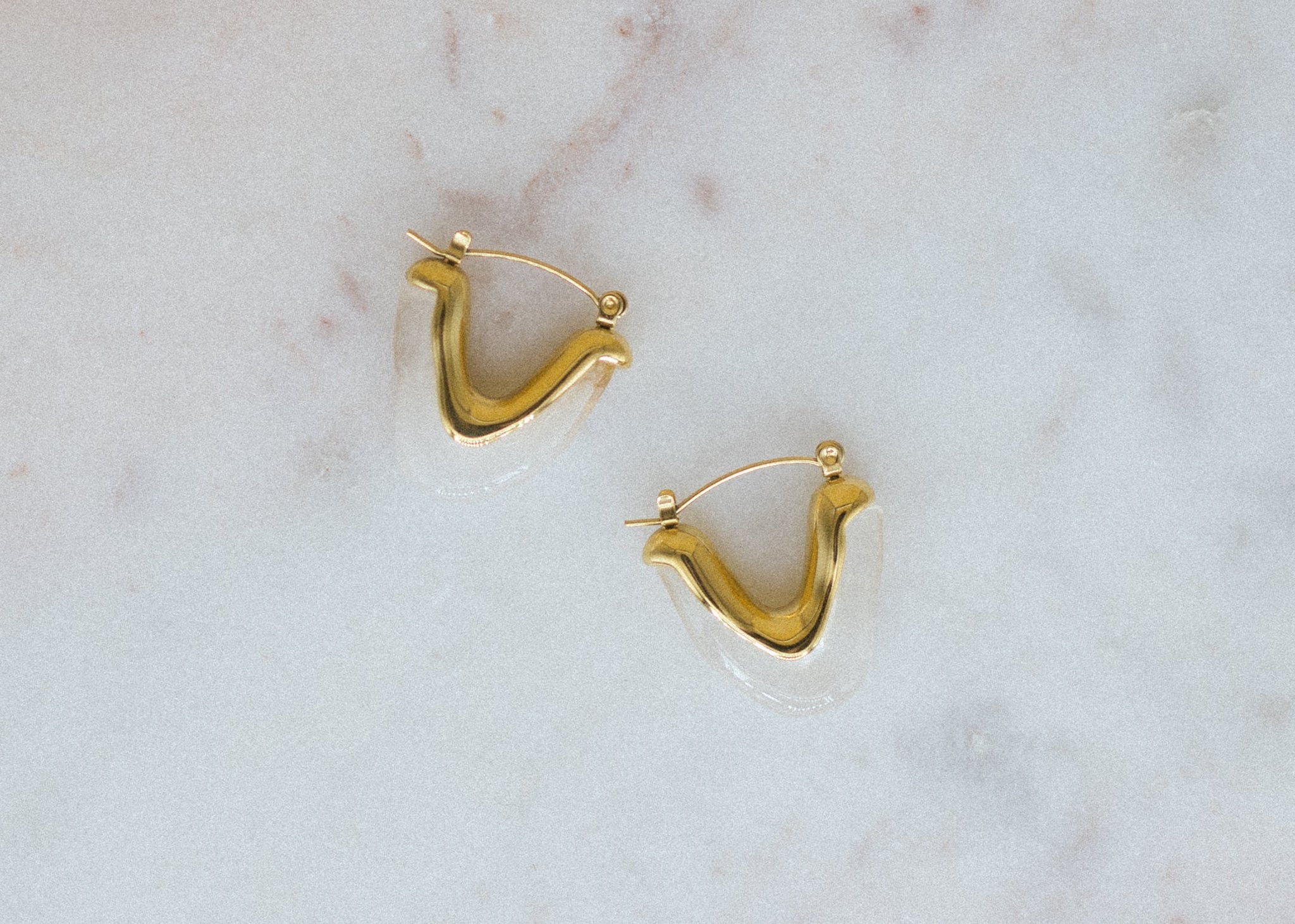 Golden Glow Hoops. Gold hoop earrings on a marble surface