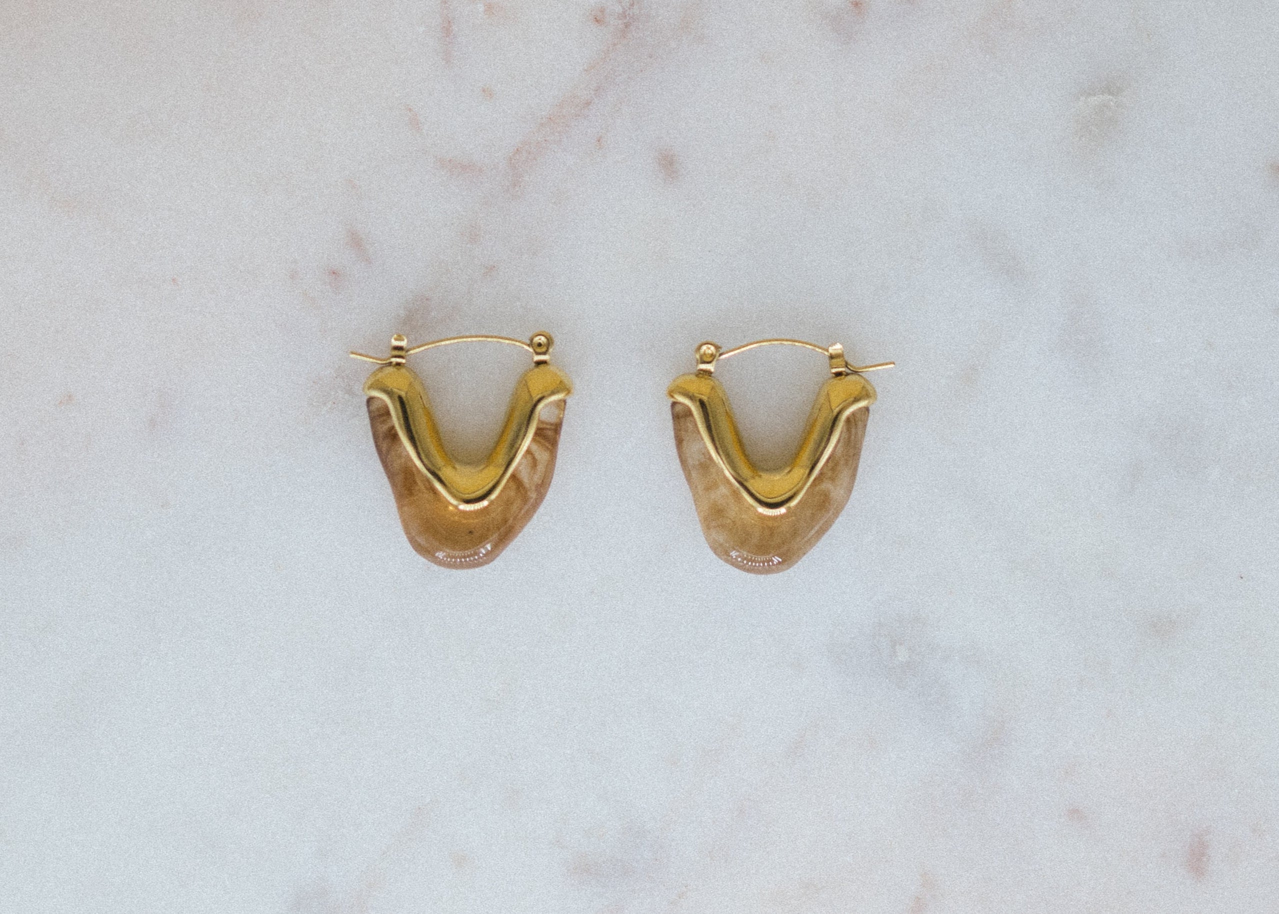 Golden Honey Hoops. Gold hoop earrings on a marble surface