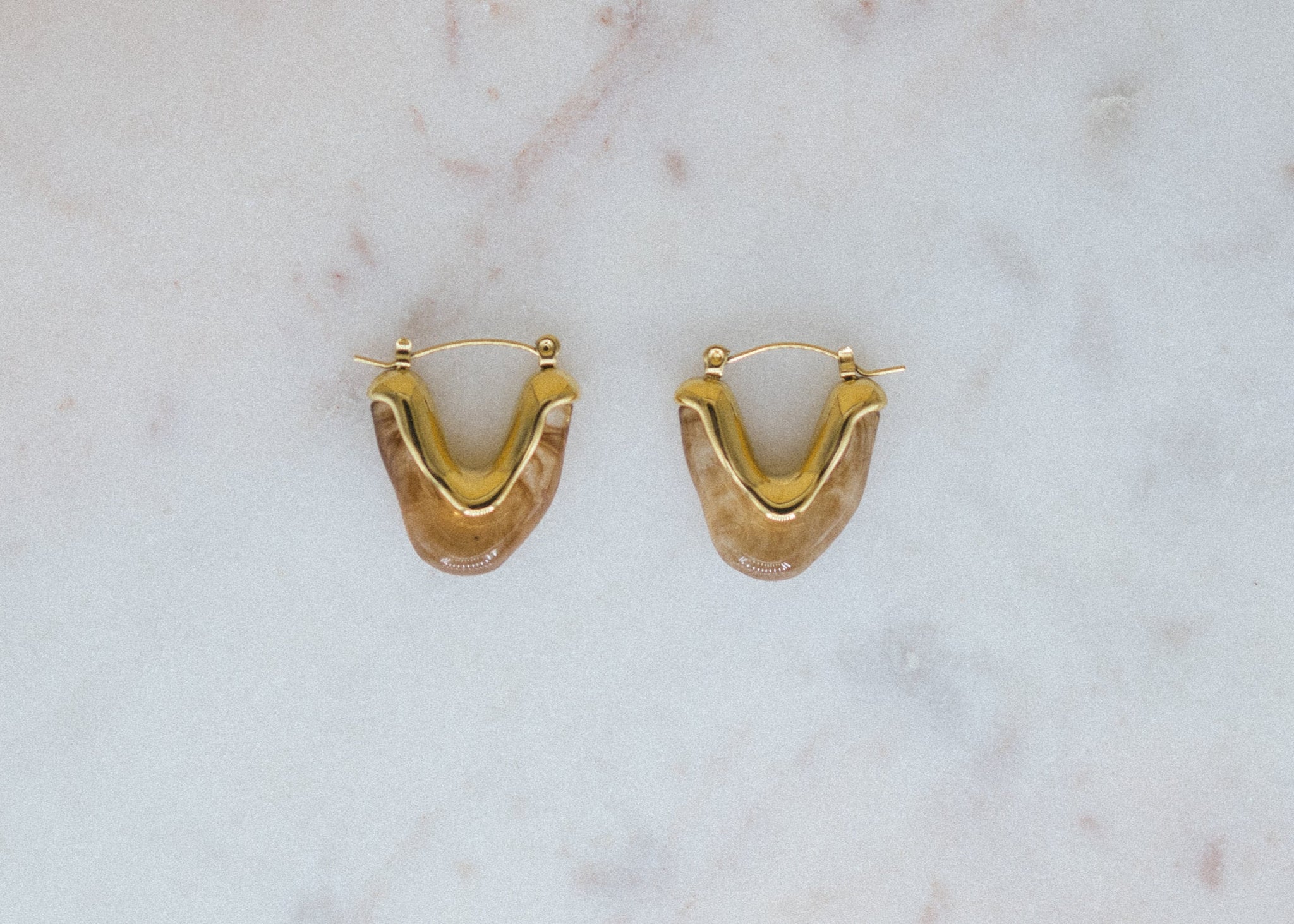 Golden Honey Hoops. Gold hoop earrings on a marble surface