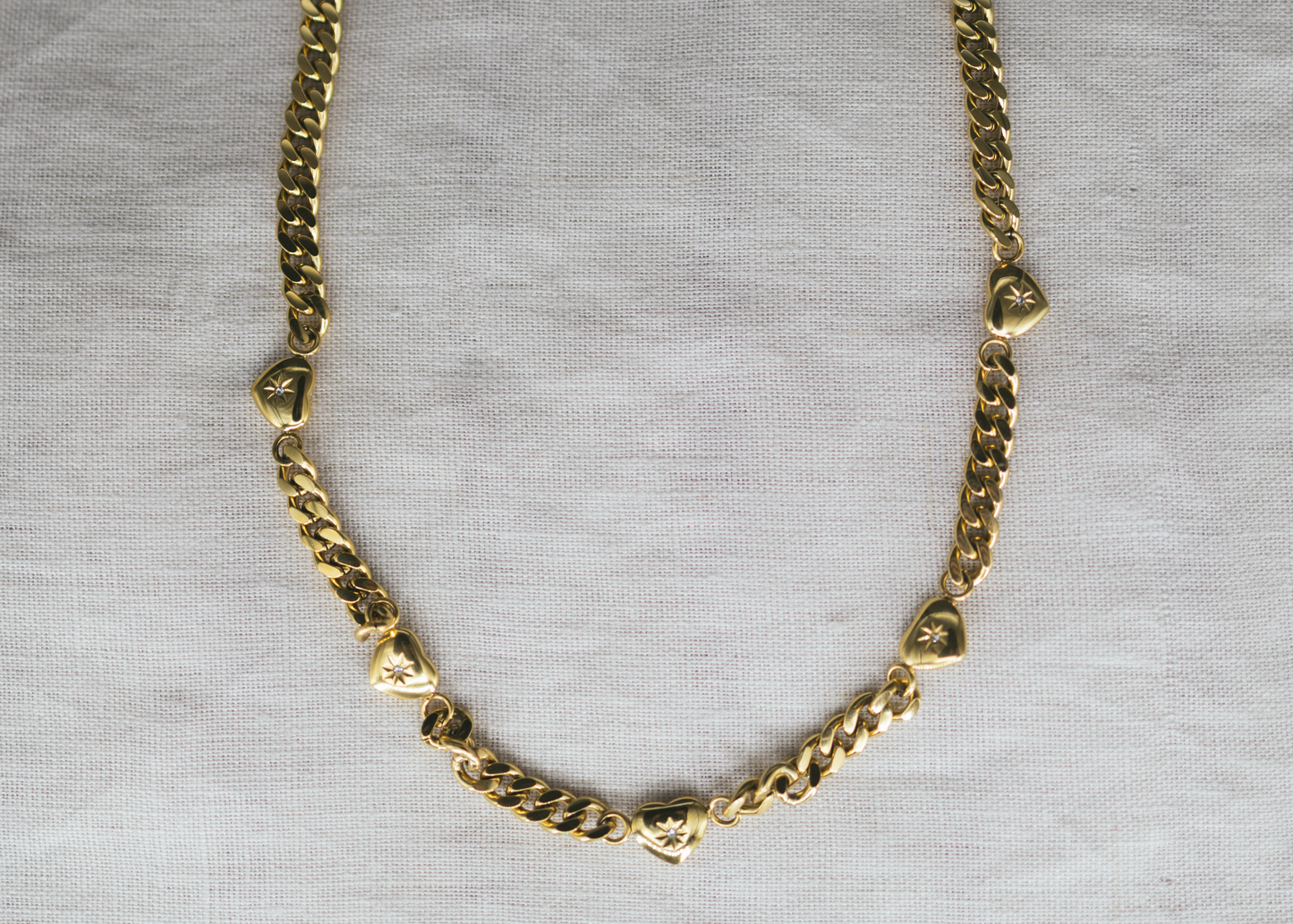 Lover’s Link -&nbsp;Gold-Plated Heart Charm Necklace. Gold chain necklace on a gray background