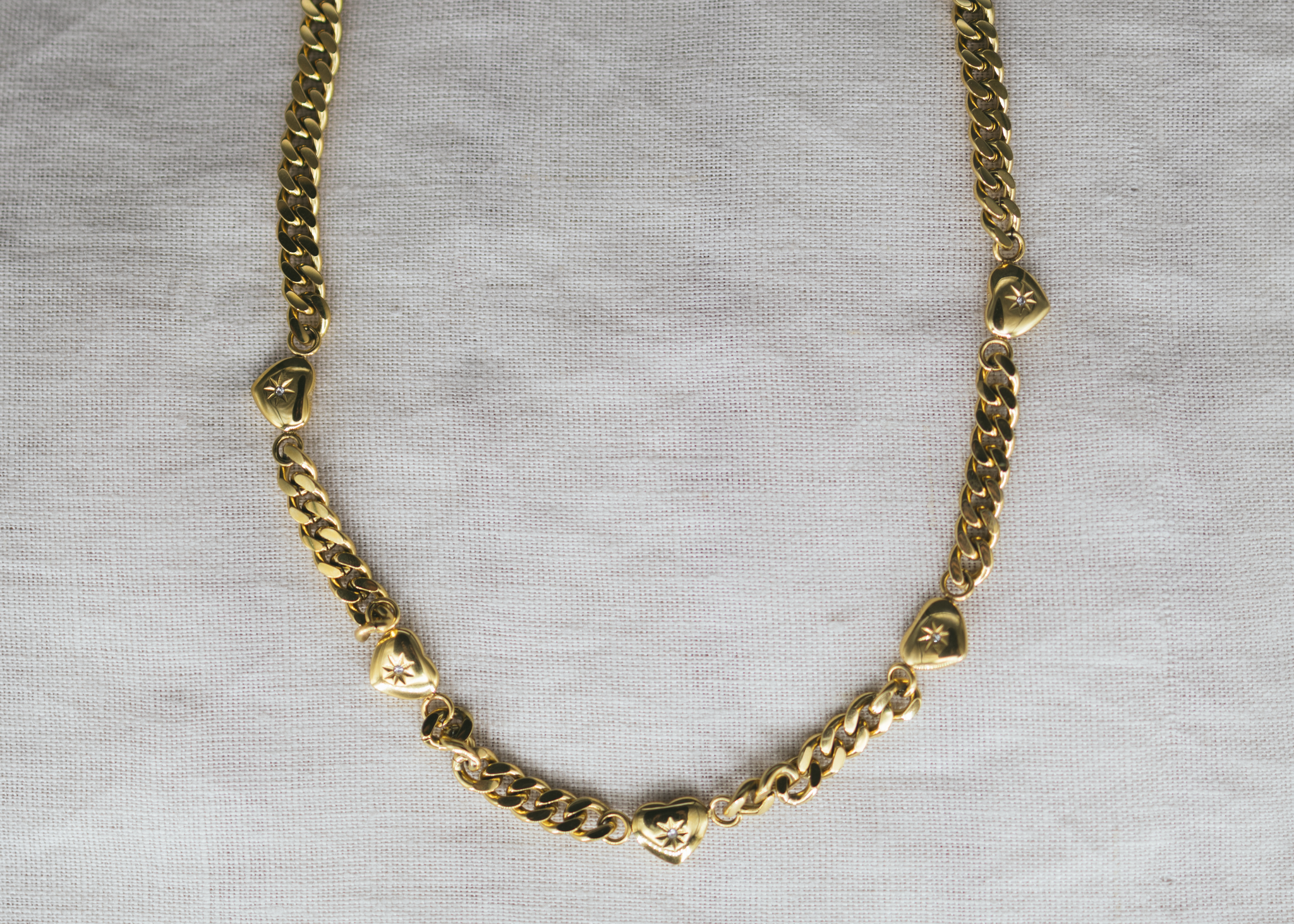 Lover’s Link - Gold-Plated Heart Charm Necklace. Gold chain necklace on a gray background