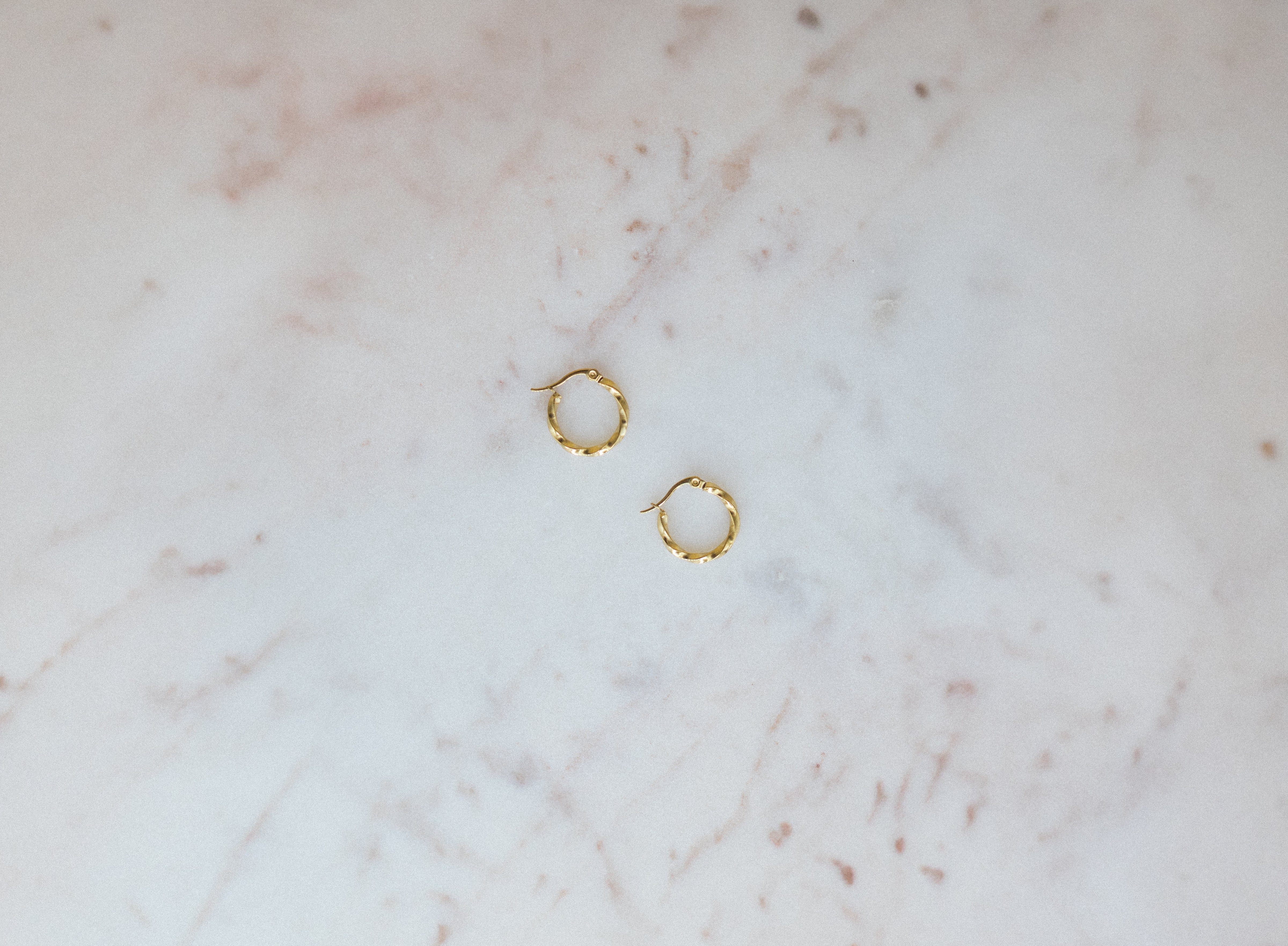 Gold hoop earrings on a marble surface