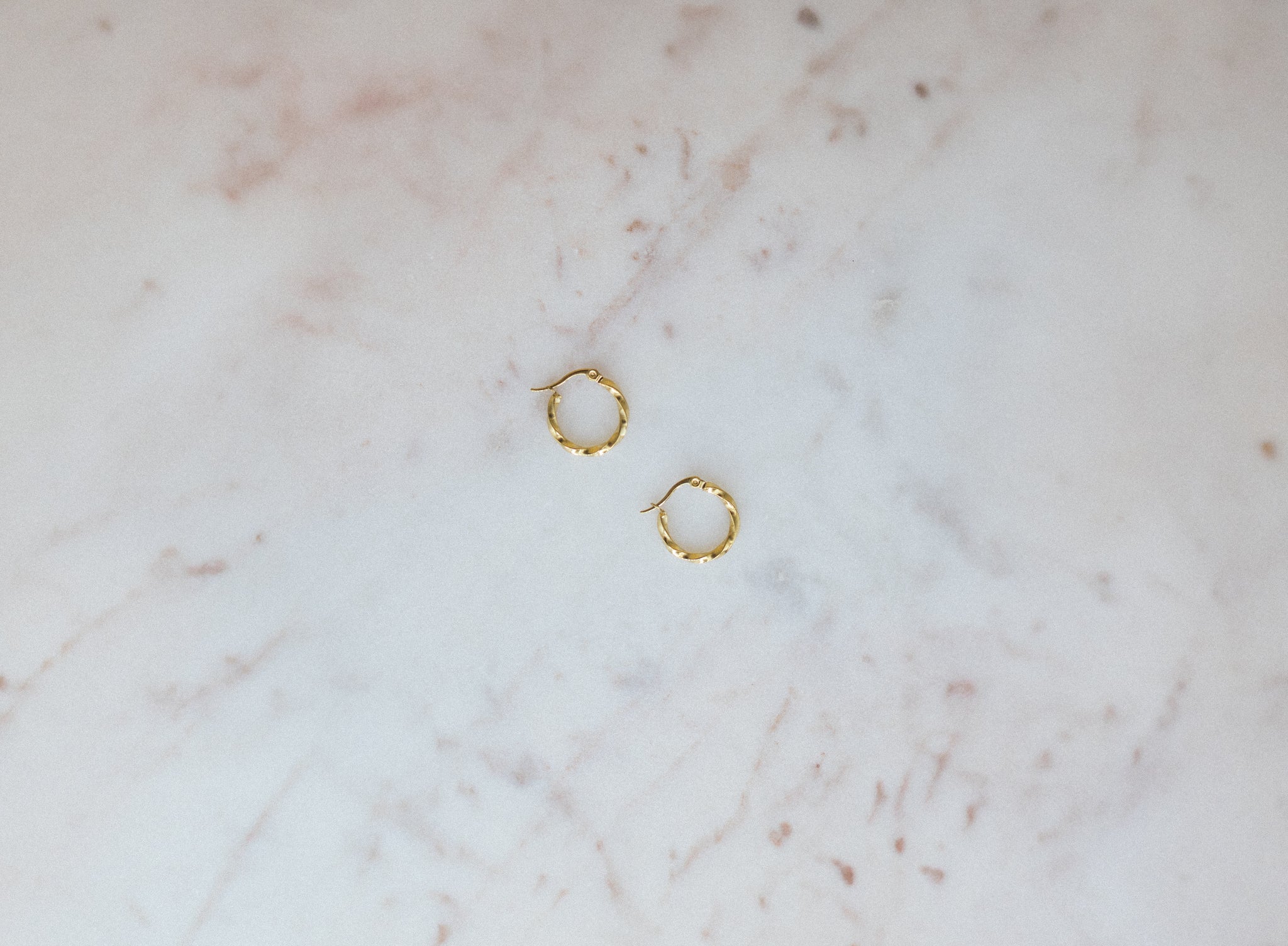 Gold hoop earrings on a marble surface
