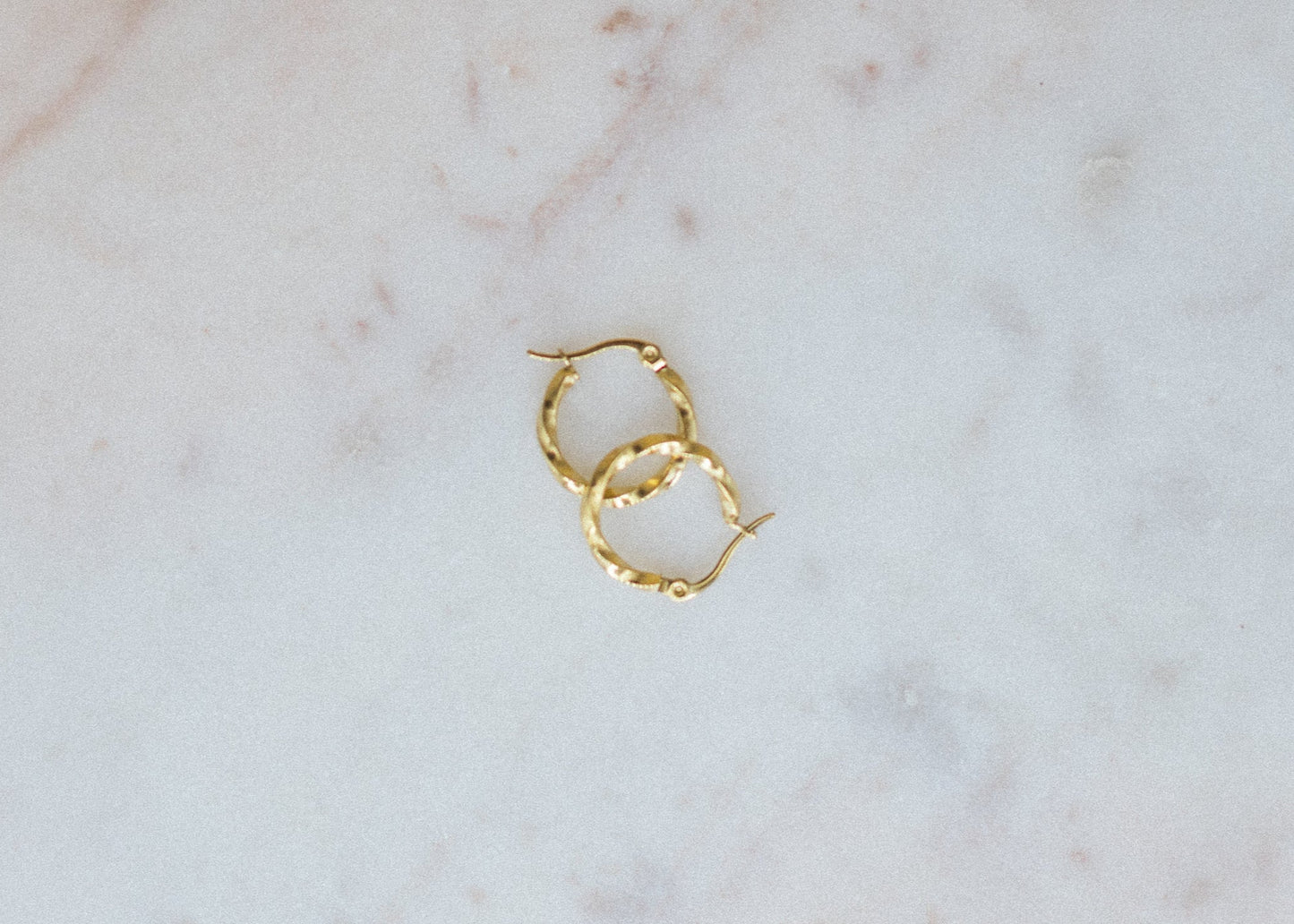 Gold hoop earrings on a marble surface