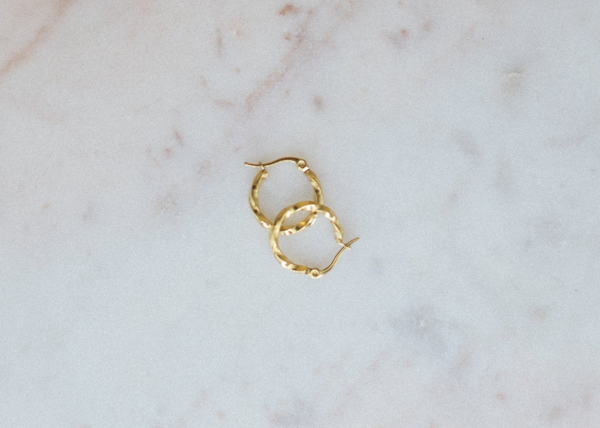 Gold hoop earrings on a marble surface