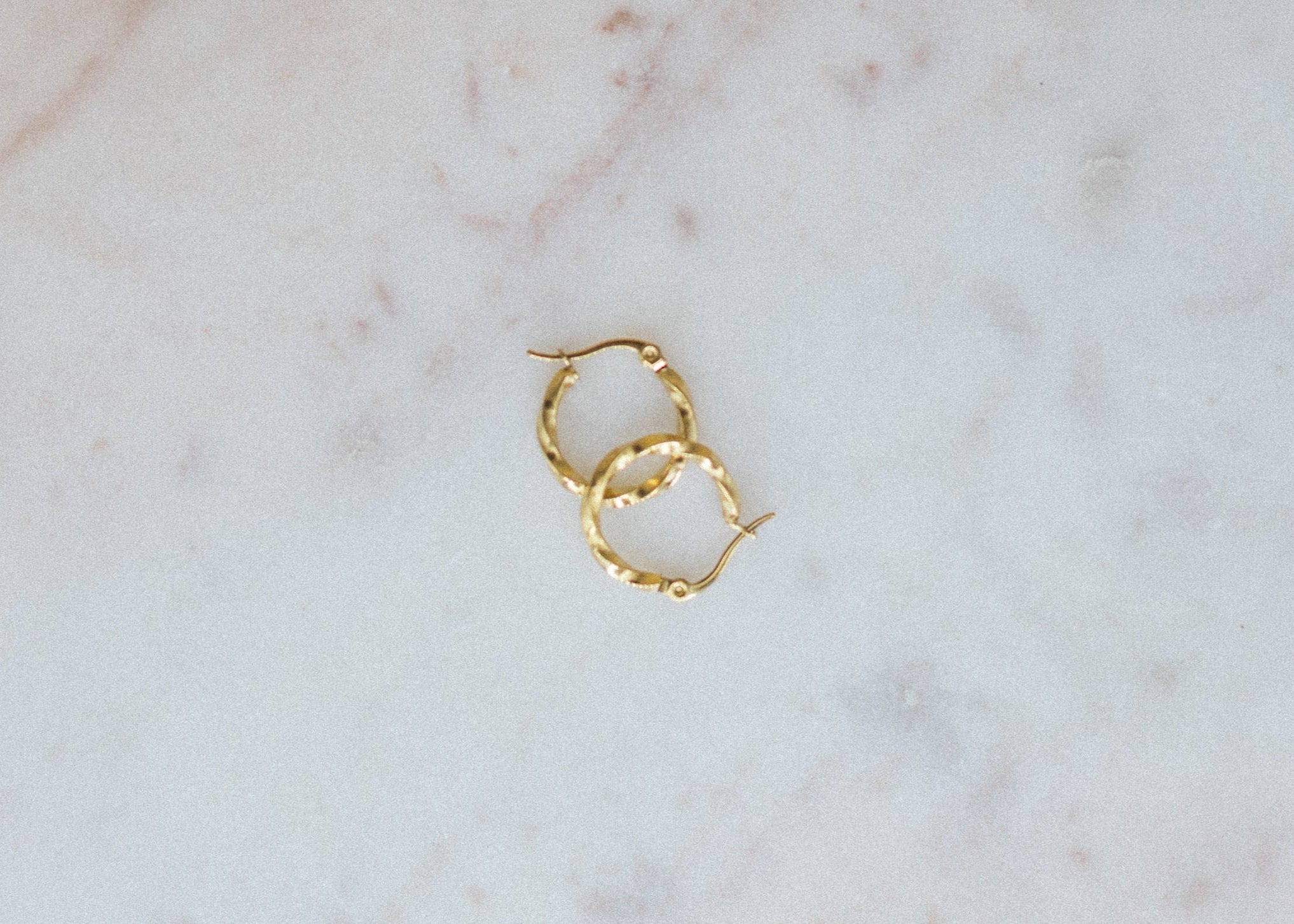 Gold hoop earrings on a marble surface
