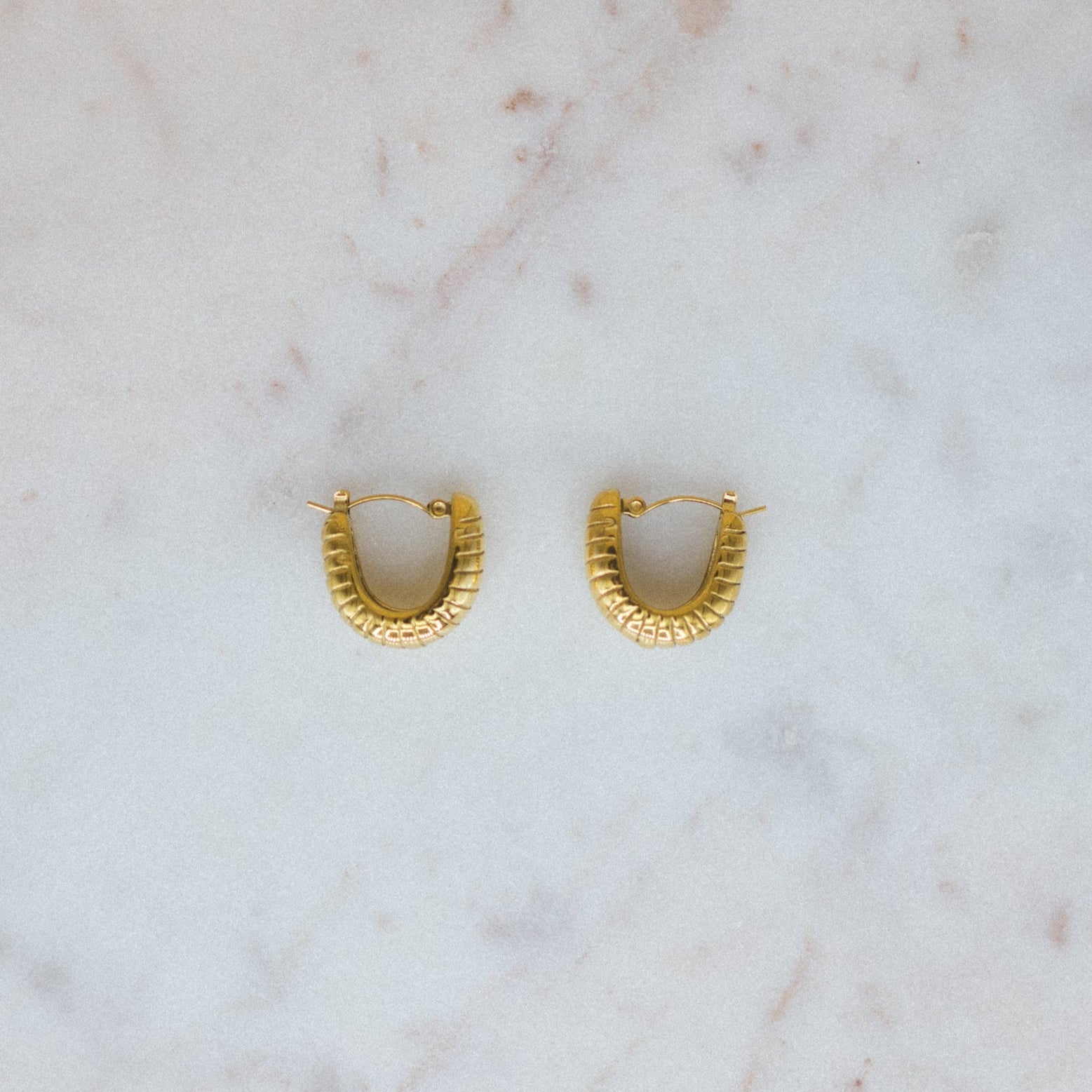 Gold hoop earrings on a marble surface
