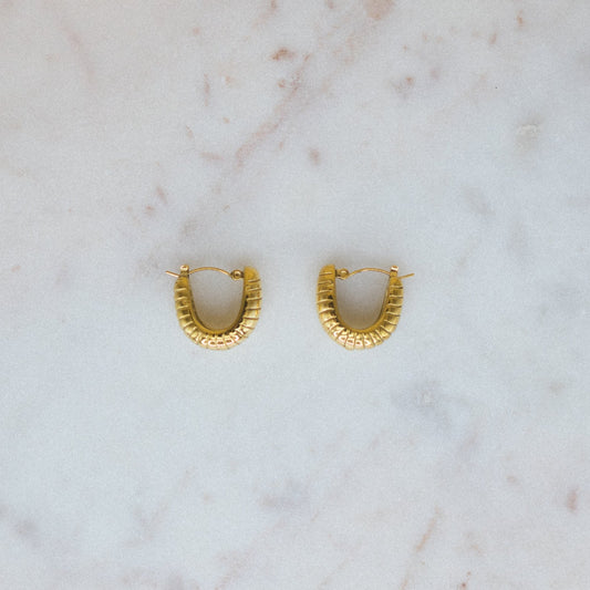 Gold hoop earrings on a marble surface