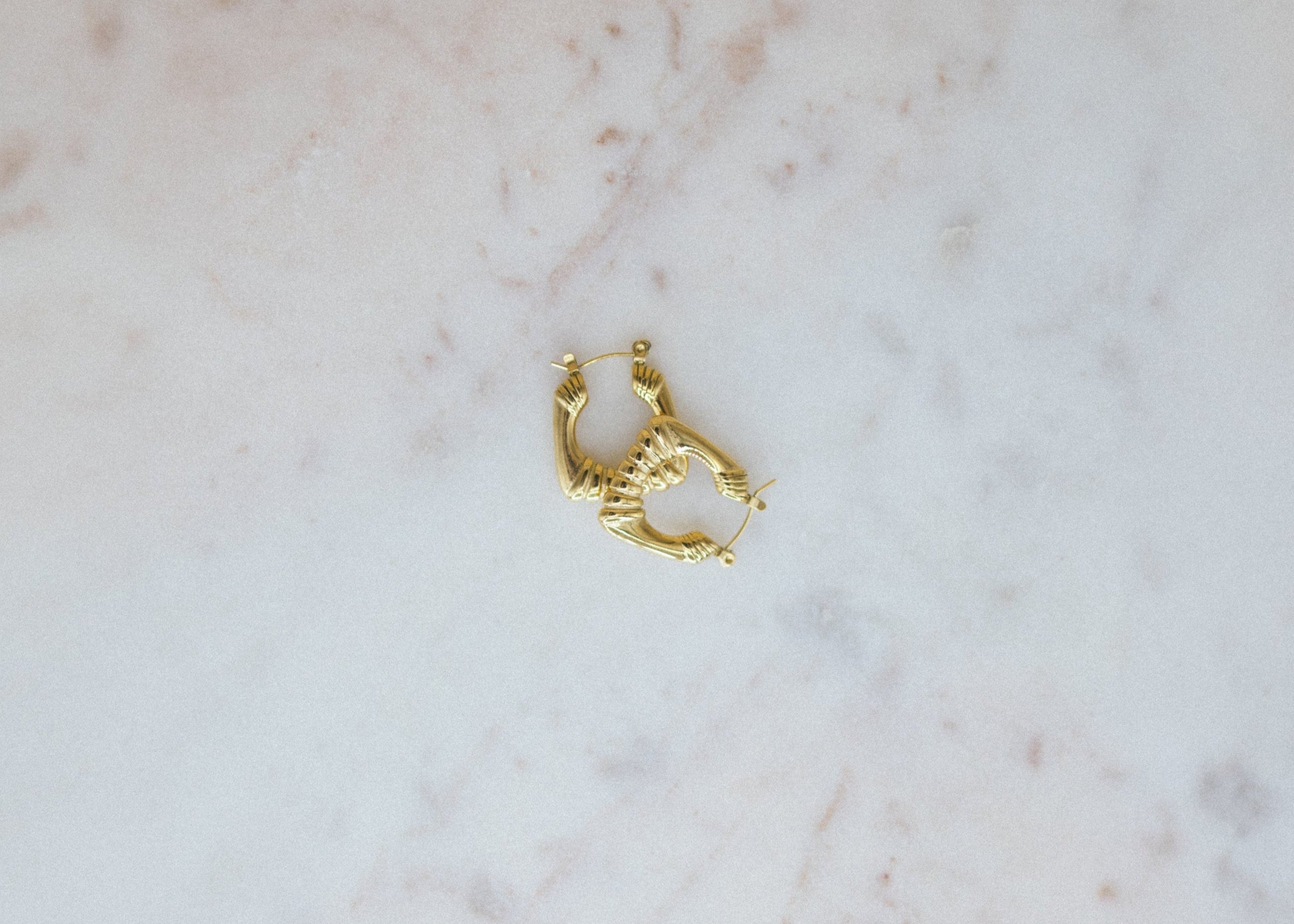 Gold hoop earring on a marble surface