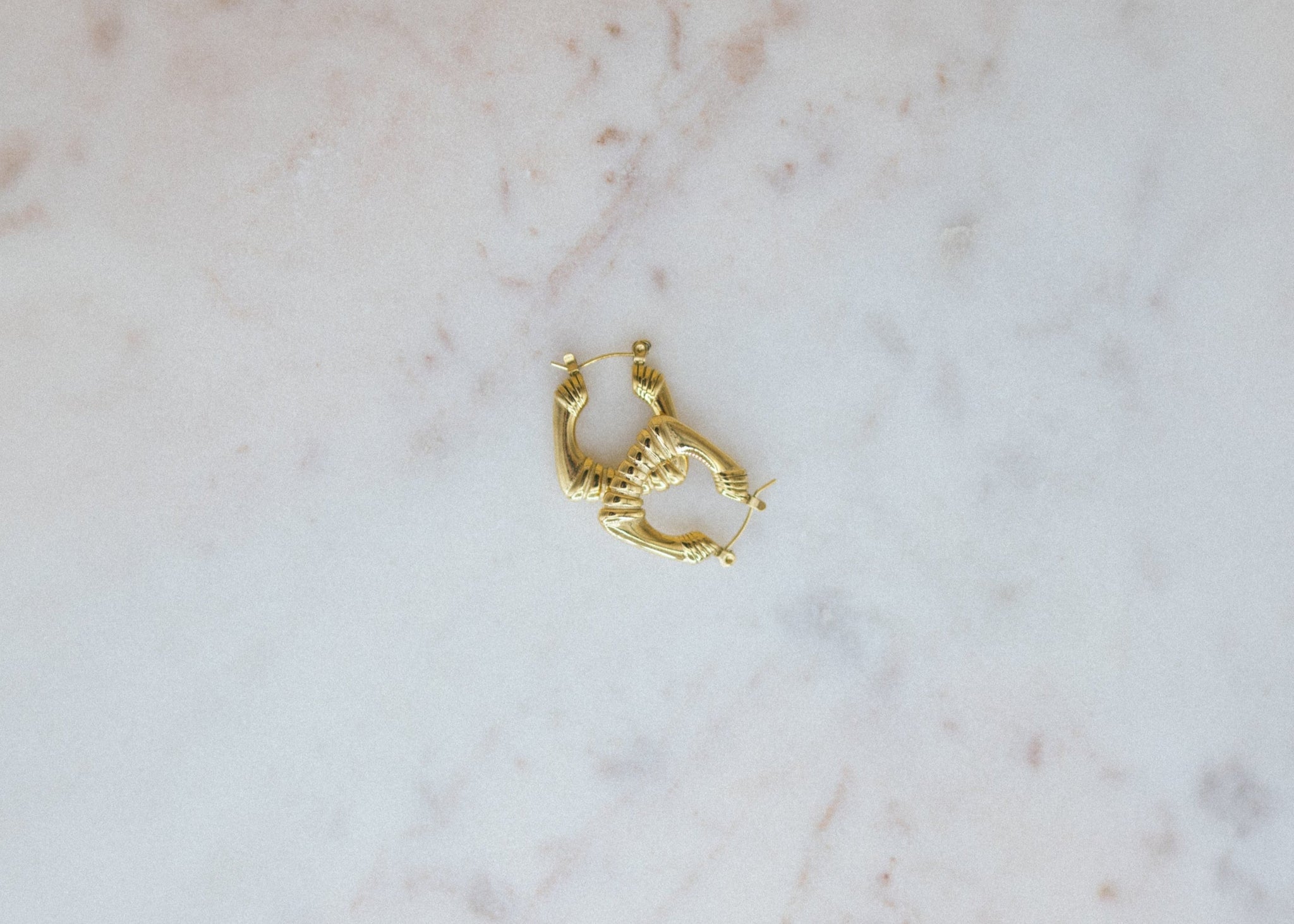 Gold hoop earring on a marble surface
