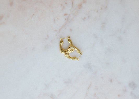 Gold hoop earring on a marble surface