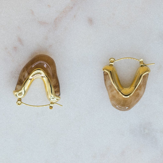 Gold hoop earrings on a light marble background