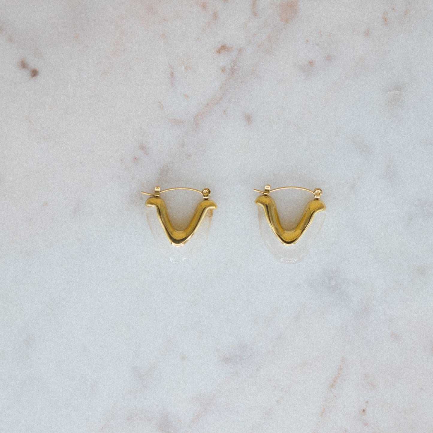 Gold earrings on a marble surface