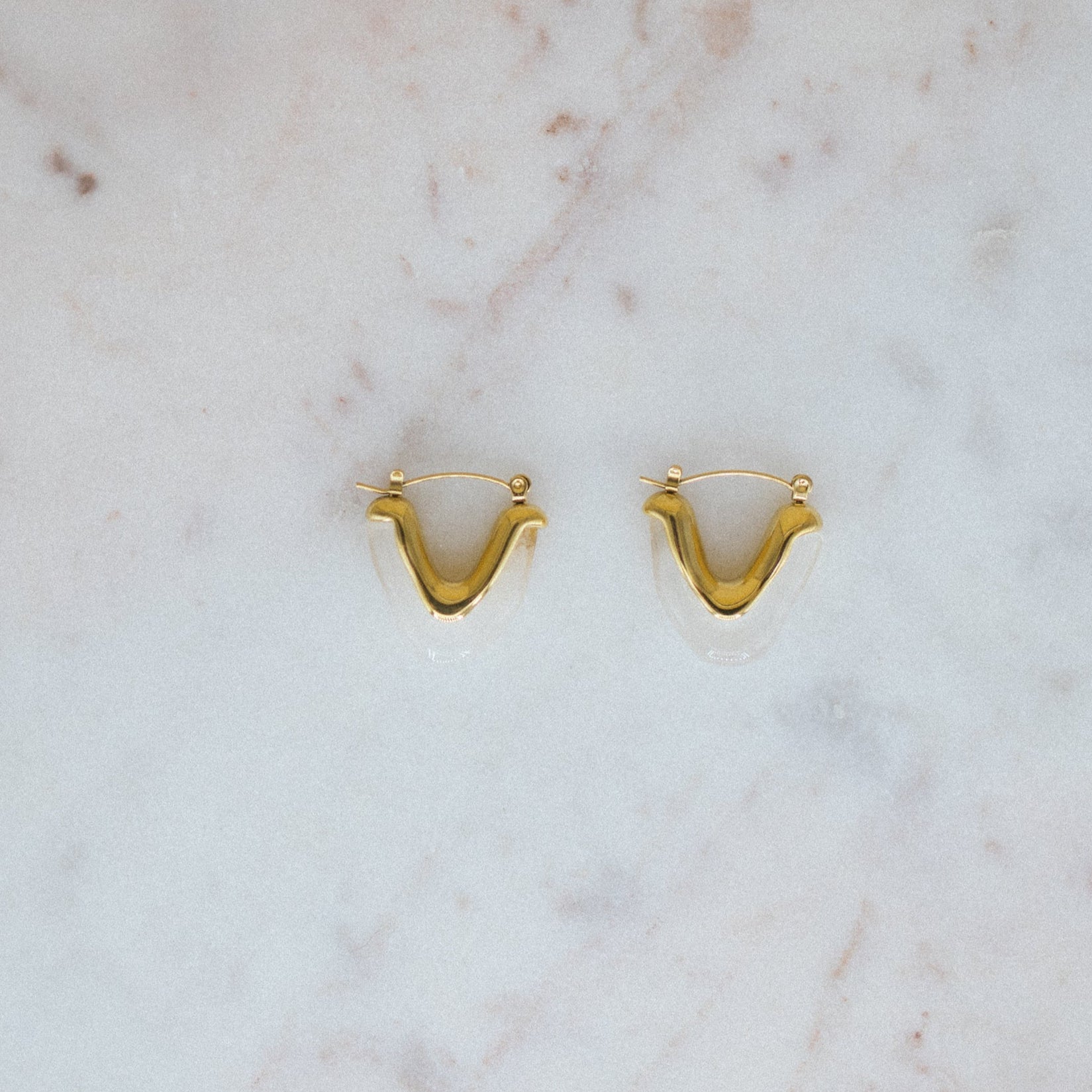 Gold earrings on a marble surface