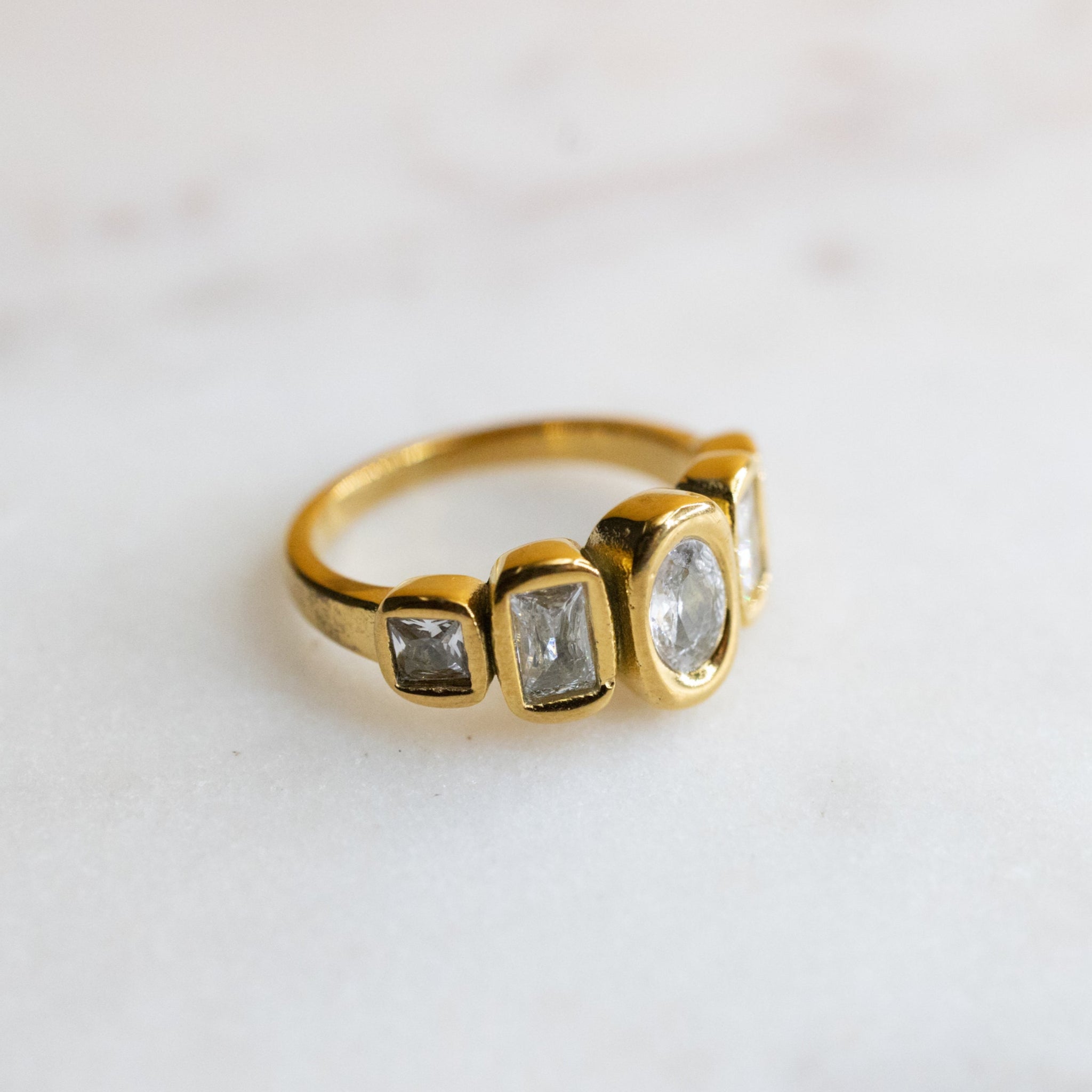 Gold ring with three gemstones on a light background