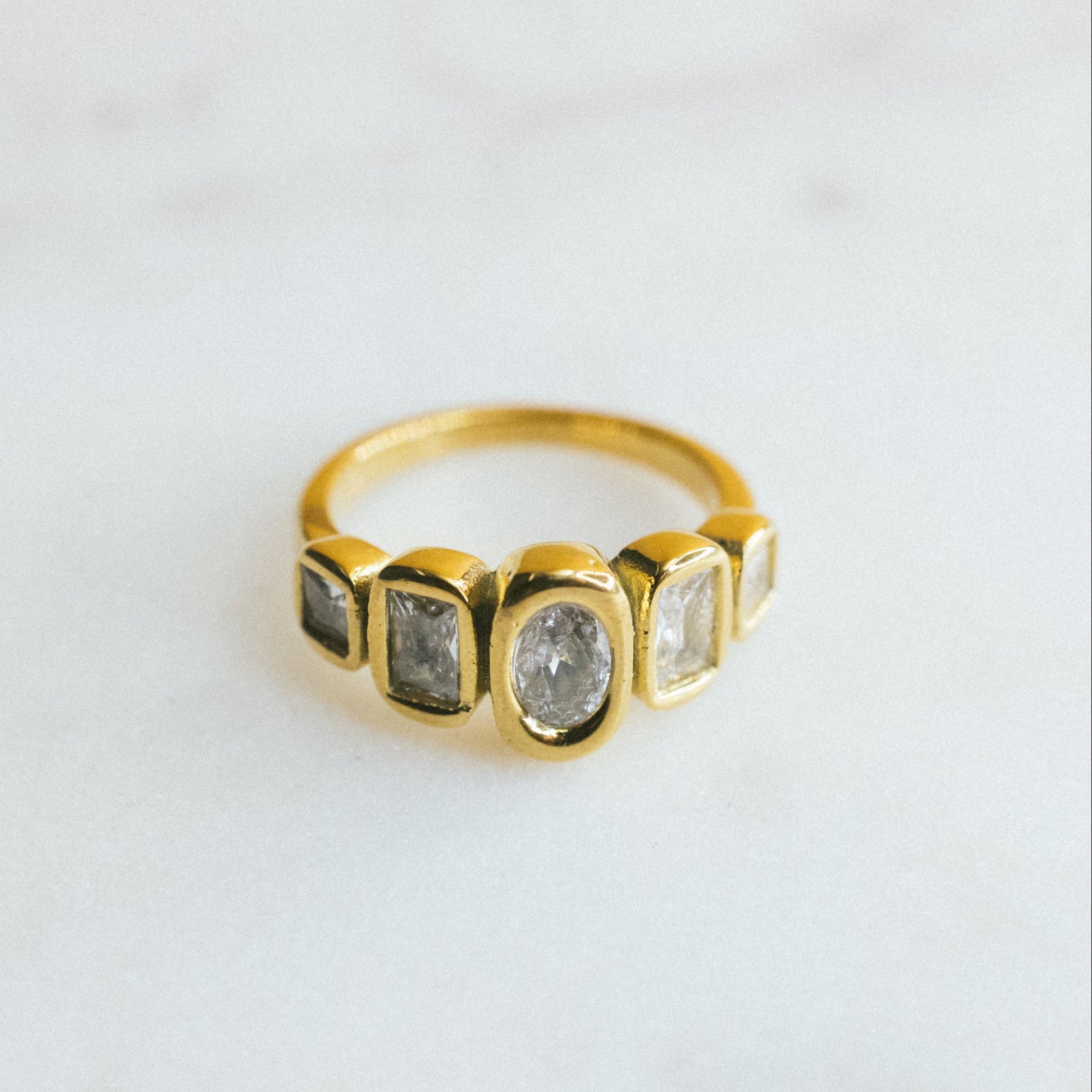 Gold ring with embedded stones on a light gray background