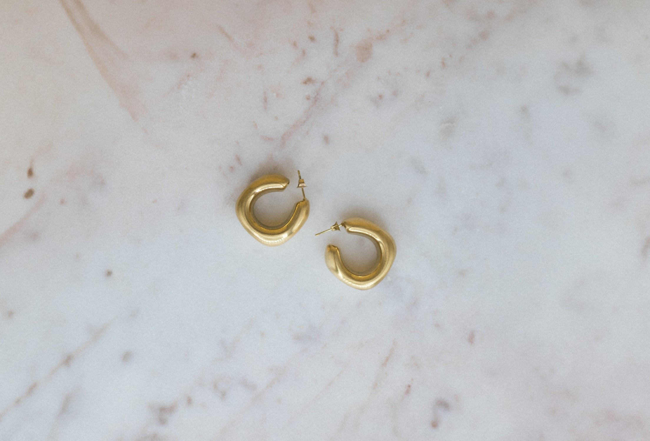 Textured Classic Luxe Hoops. Gold hoop earrings on a marble surface