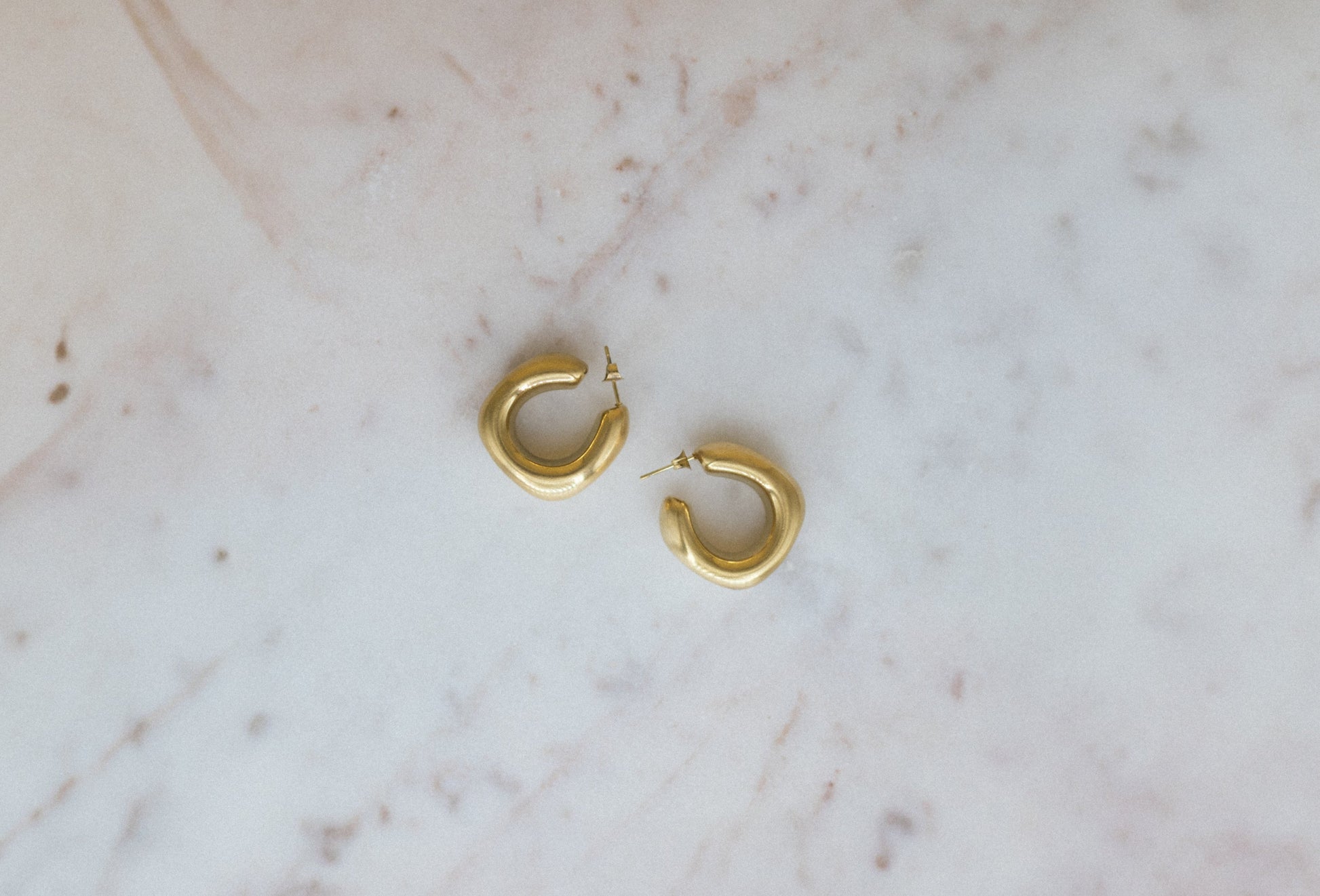 Textured Classic Luxe Hoops. Gold hoop earrings on a marble surface
