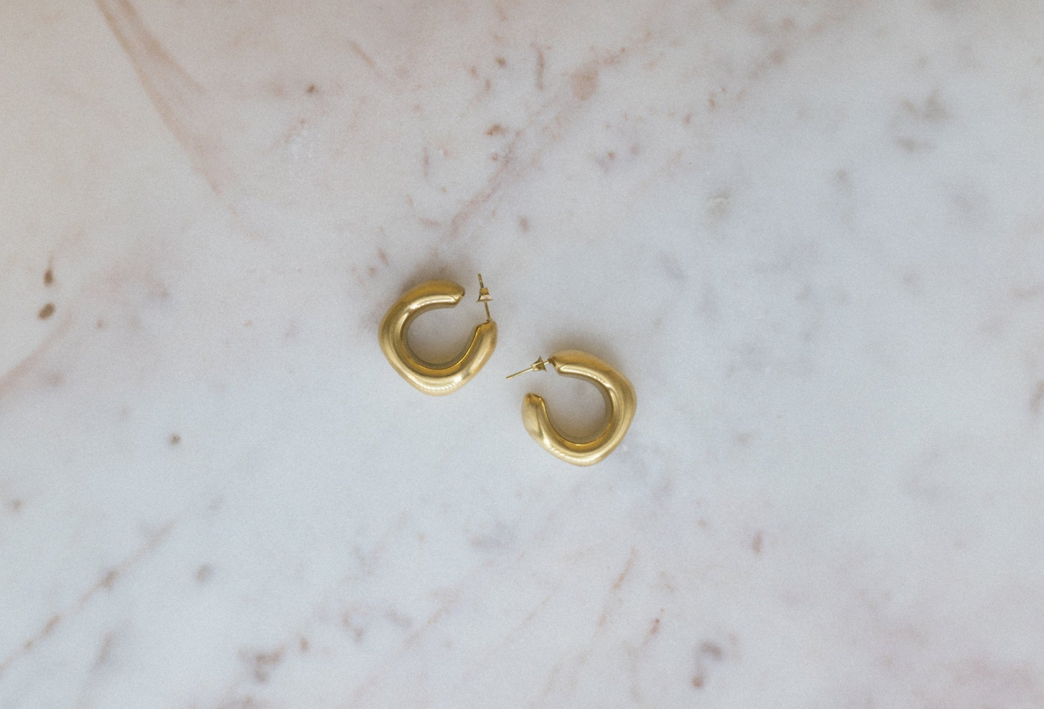Textured Classic Luxe Hoops. Gold hoop earrings on a marble surface