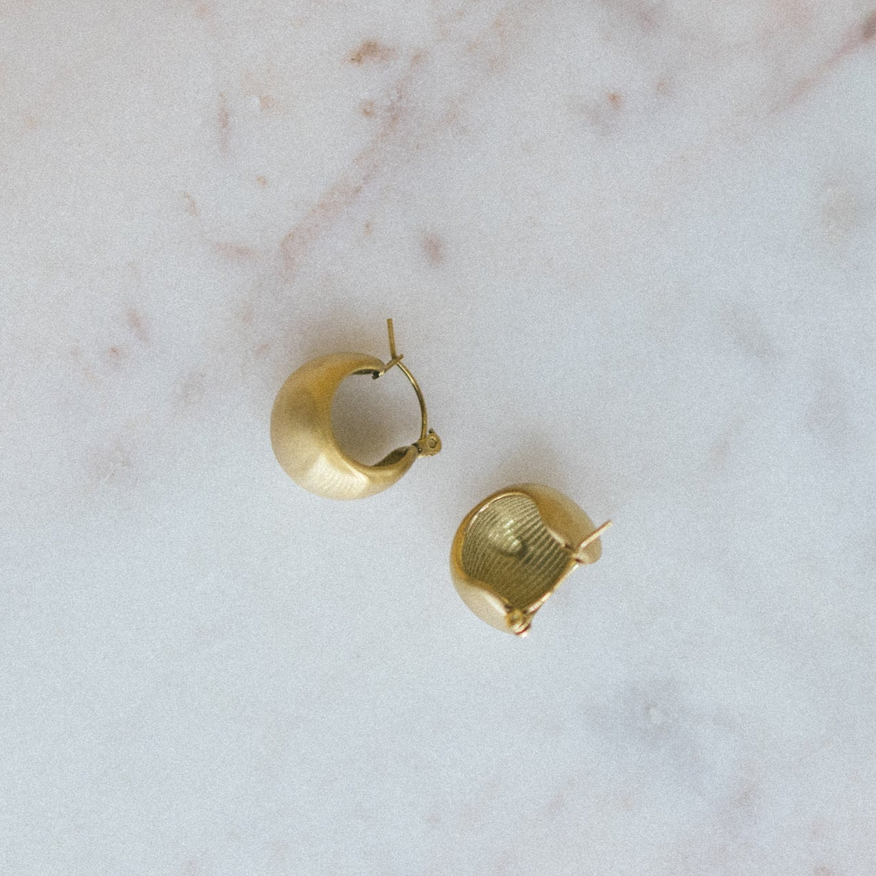 Gold hoop earrings on a marble surface