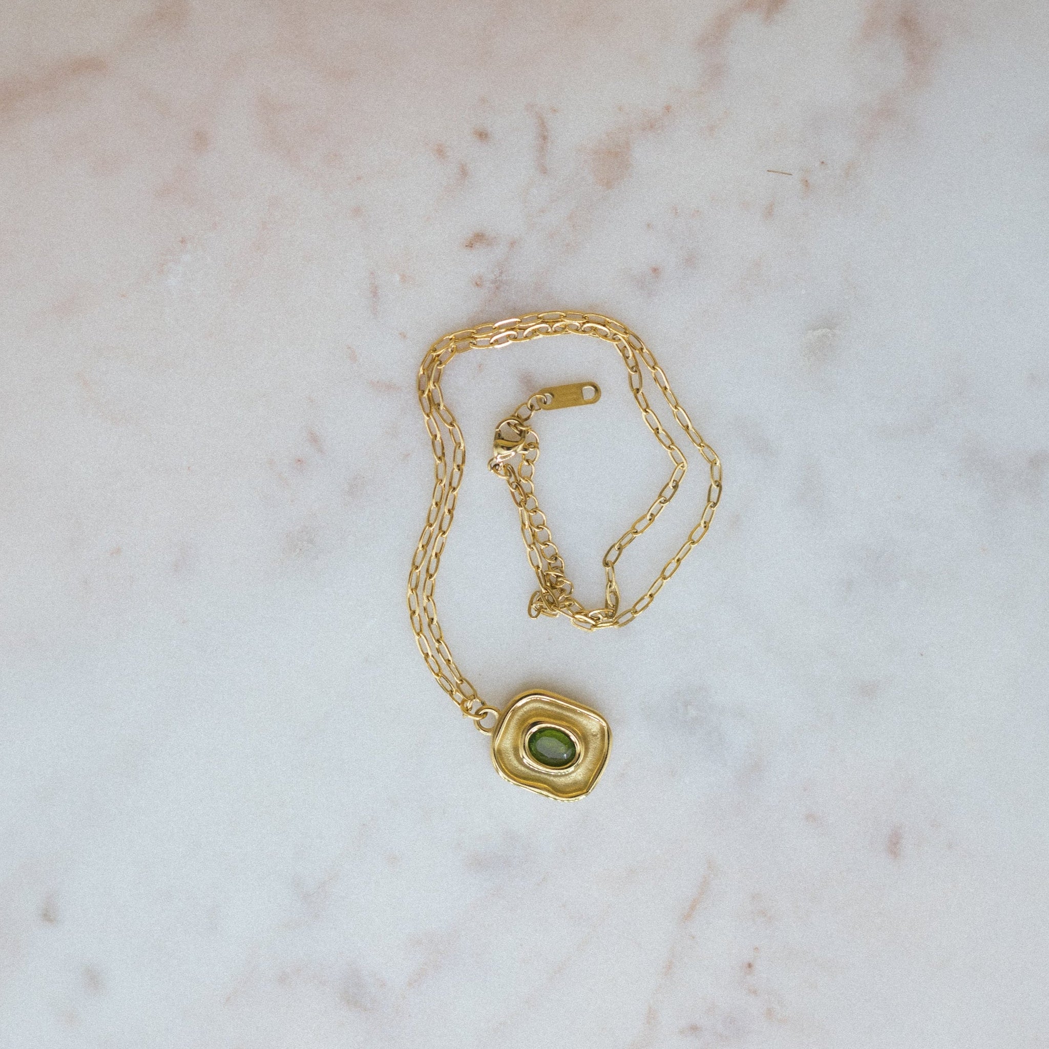 Luxe Leaf Pendant - green zircon pendant necklace lying on a canvas, rolled up, for display