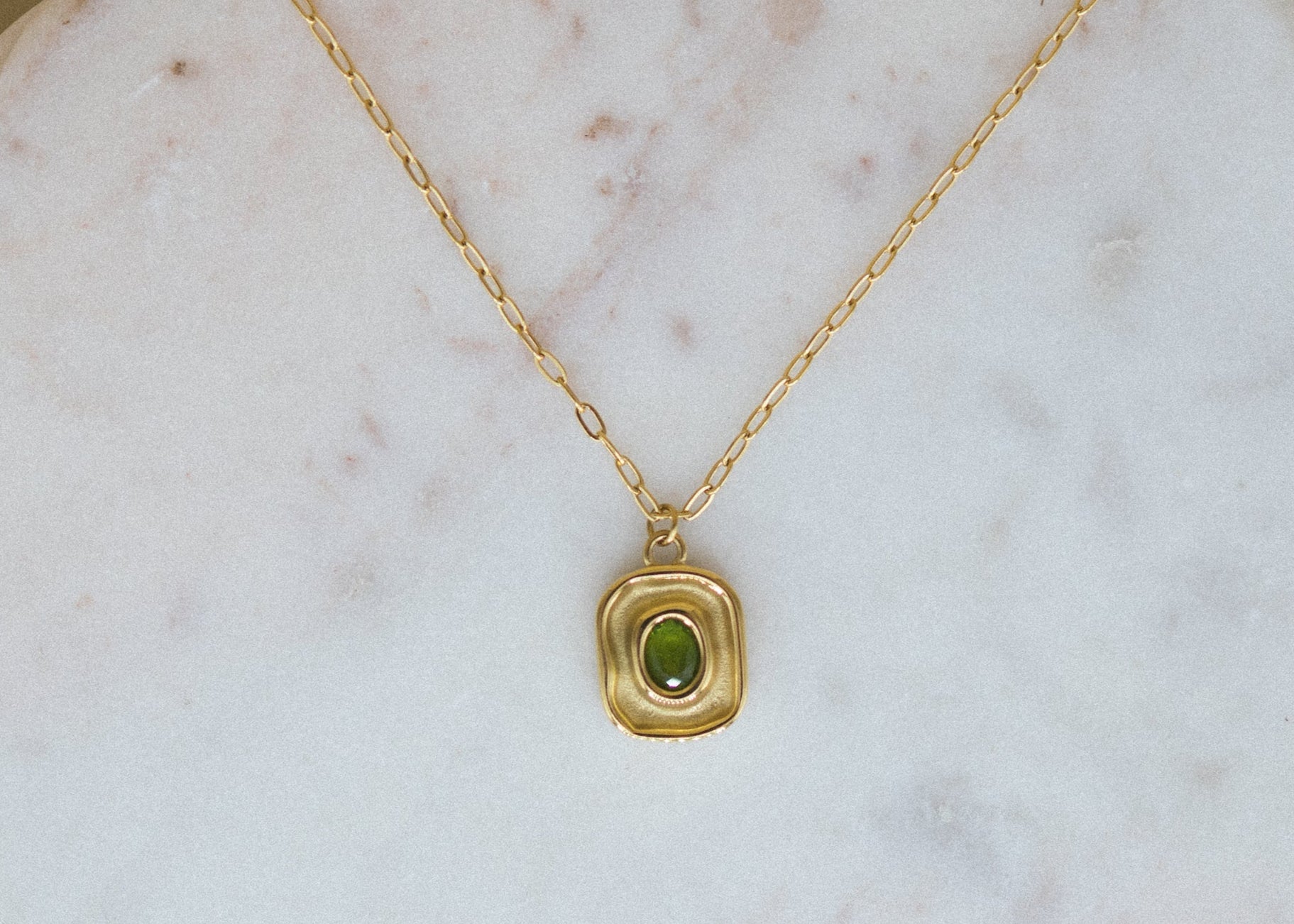 Luxe Leaf Pendant - green zircon pendant necklace lying on a canvas for display