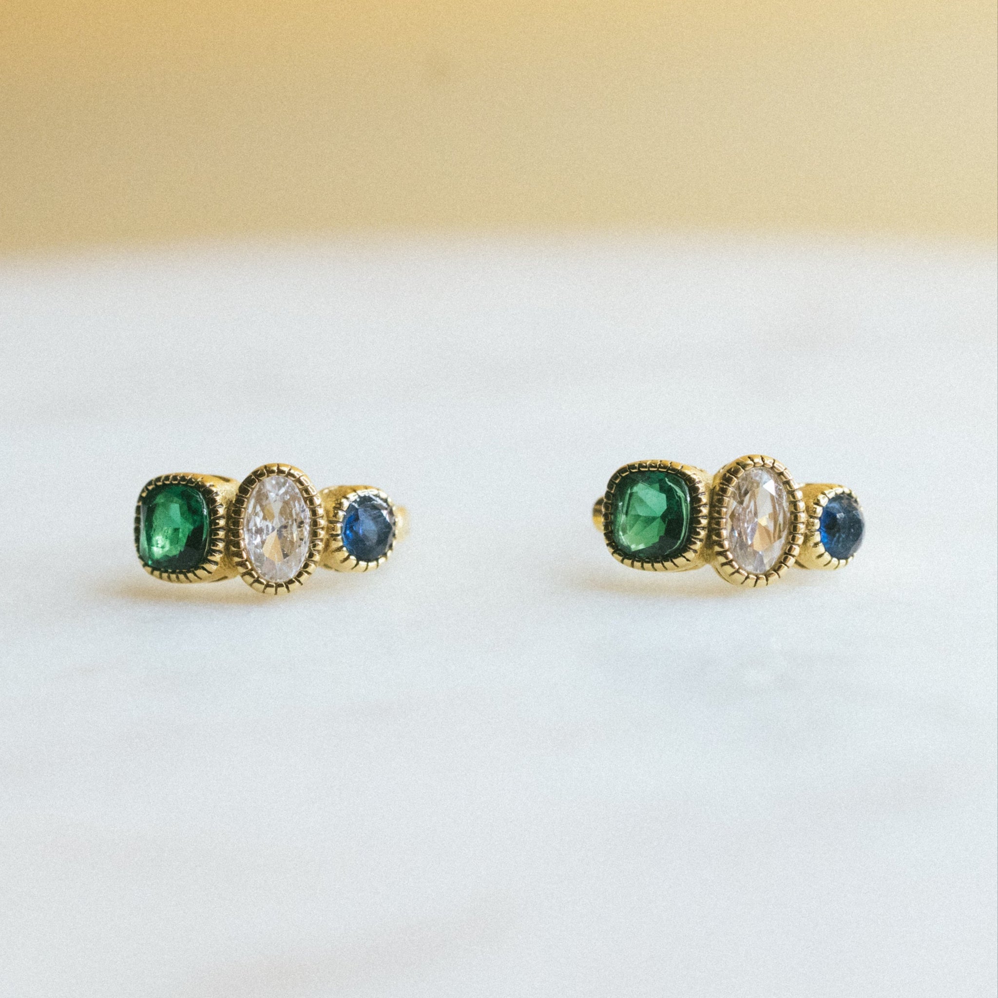 Pair of gold earrings with gemstones on a light background