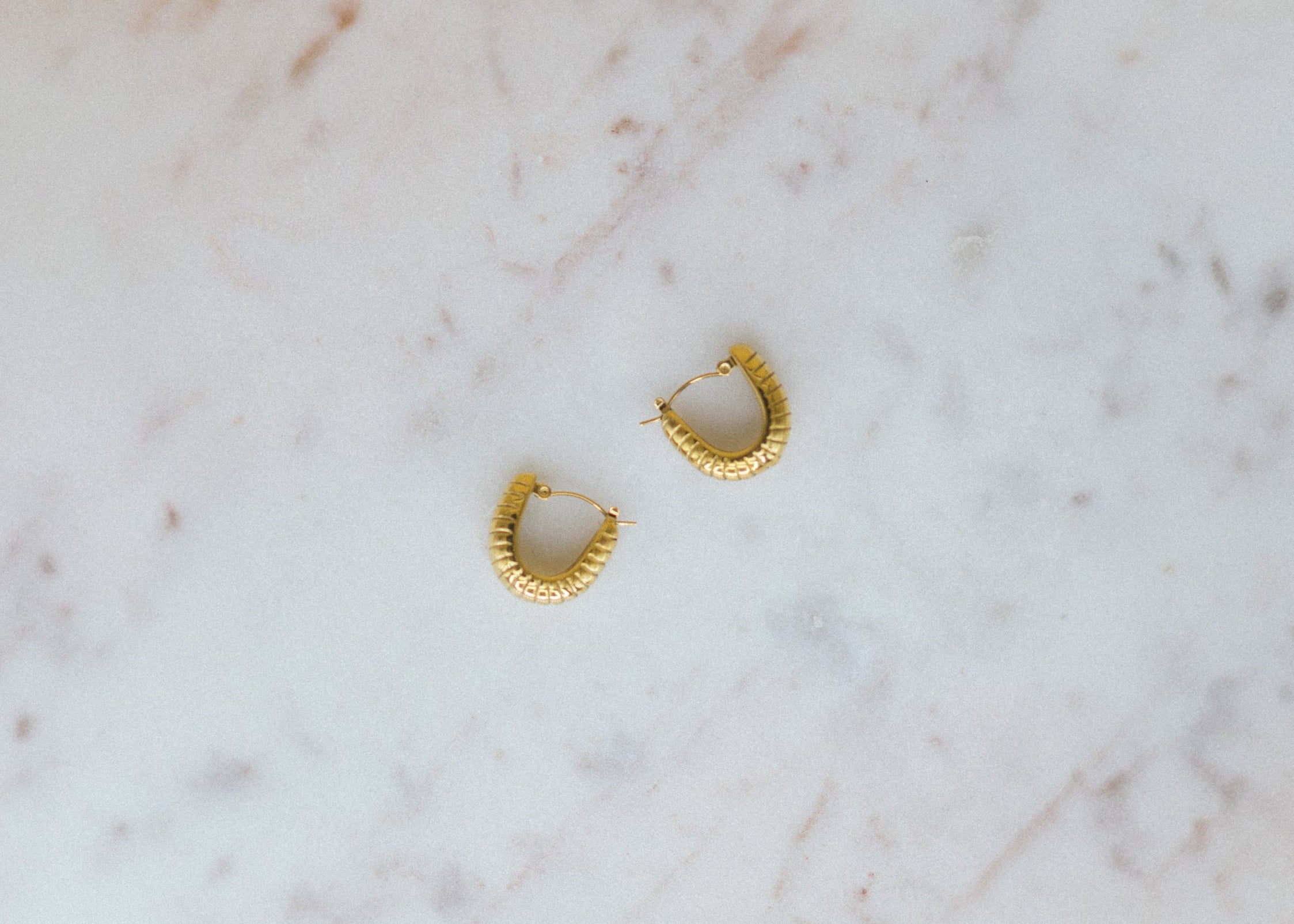 the classic u. Gold hoop earrings on a marble surface