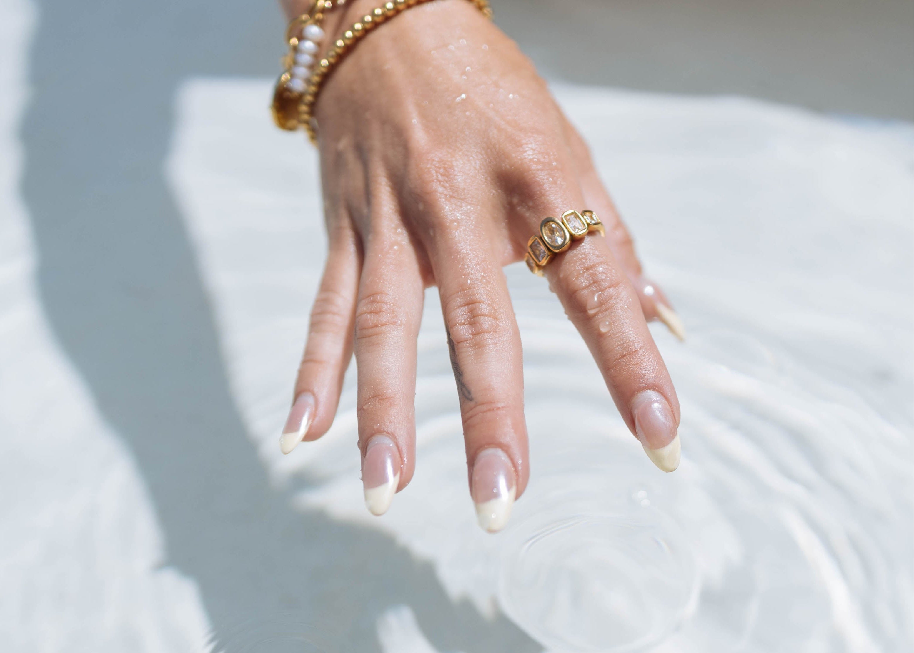 Hand with gold rings and bracelets on a white background